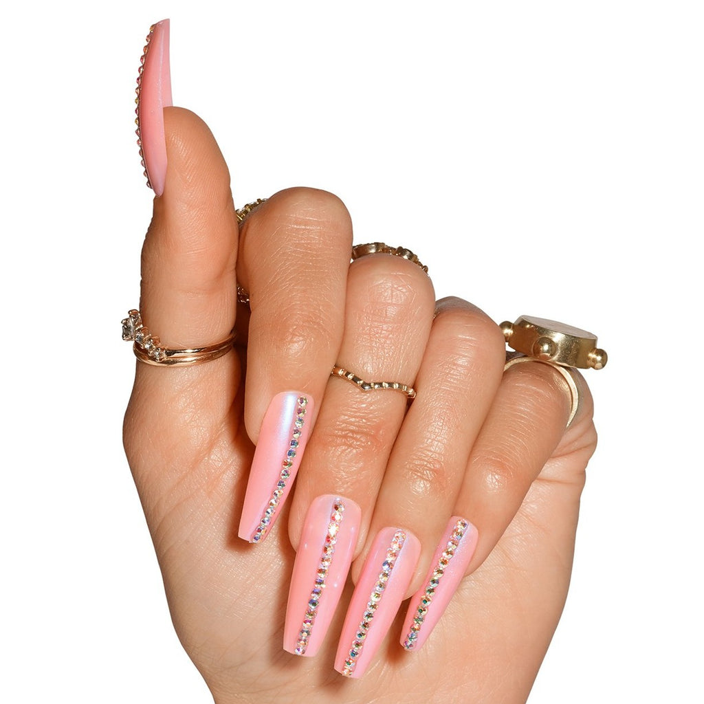 Hand wearing Princess Cut nails in Ultra Long Coffin, pink nails with blue shimmer and row of diamontes down centre of nails
