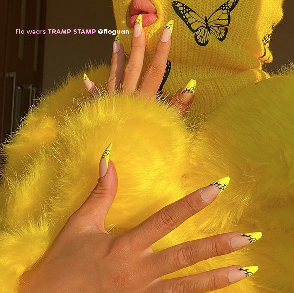 Influencer wearing Tres She instant acrylic press on nails in neon yellow French tips with tattoo print long tapered ballerina shape